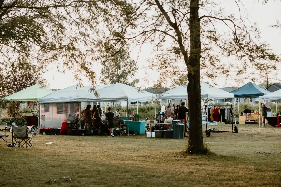 Vendor tents under the trees at the Backyard Market on a Thursday evening